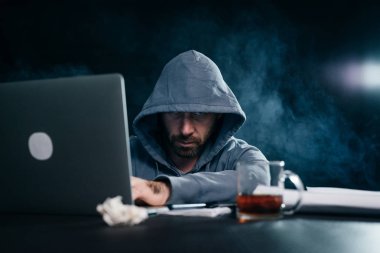 bir dizüstü bilgisayarda yasadışı bir şey yapıyor onun yüzünü gizleme suç gizemli erkek bir hacker