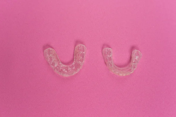 На розовом фоне лежат пластины для коррекции зубов — стоковое фото