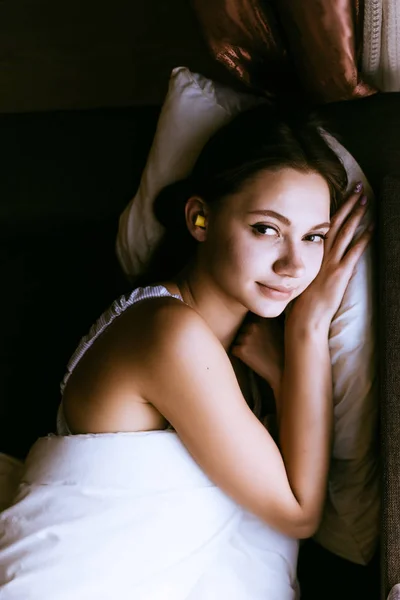 眠そうな少女は、耳の中のベッドへ騒音に対して黄色の耳栓 — ストック写真