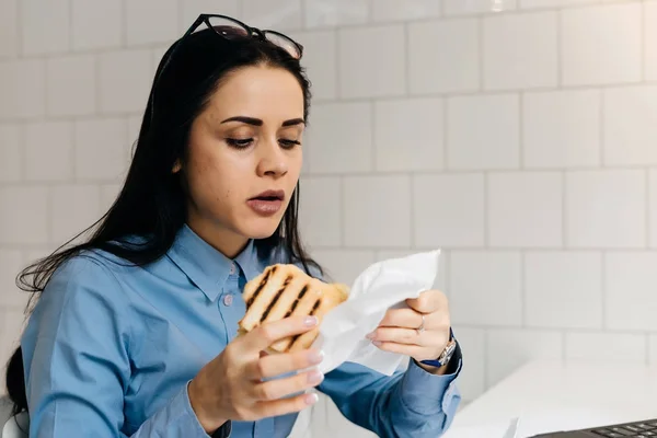 カフェでサンドイッチを食べる若い美しいブルネットの少女 — ストック写真