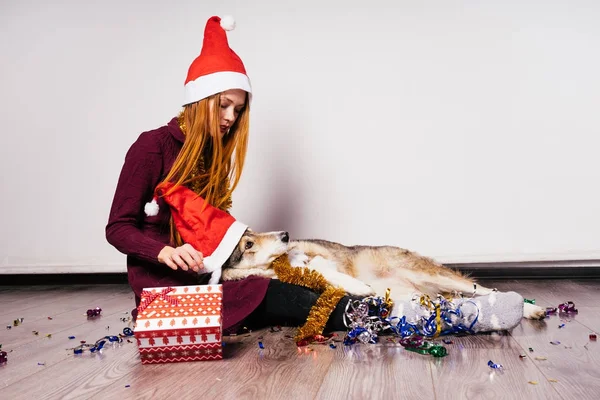 Руда дівчина сидить на підлозі зі своєю собакою, чекаючи на новий 2018 рік, багато мішури і подарунка — стокове фото