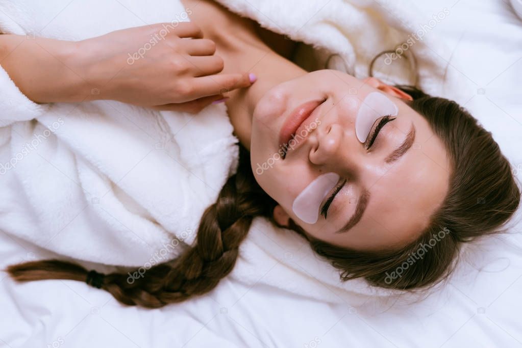 smiling happy girl lies in bed, under eyes white patches, eyes closed