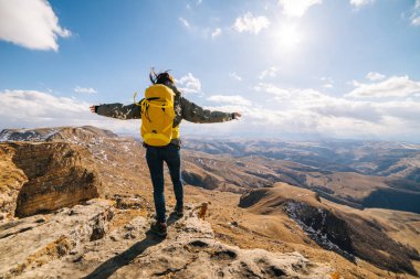 mutlu genç kız sarı bir sırt çantası ile yolculuk beyaz ridge, hava ve dağlar sahiptir