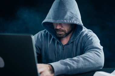 gizemli suç adam yüzünü başlık, bir hacker altında gizler, bir dizüstü bilgisayarda çalışır