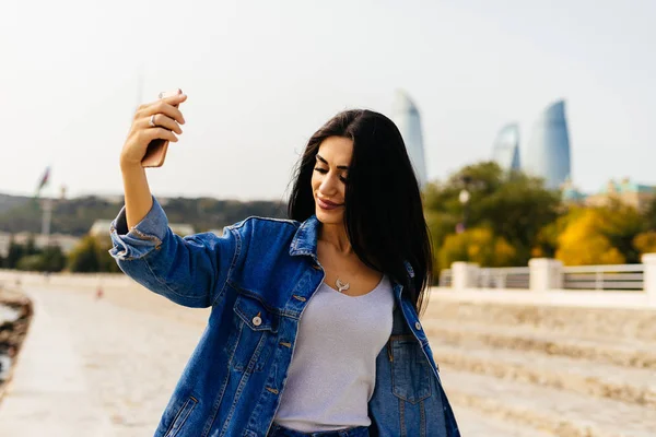 Czarnowłosa dziewczyna stylowe podróżuje przez Azerbejdżan, sprawia, że selfie na tle nowoczesnych budynków w Baku — Zdjęcie stockowe