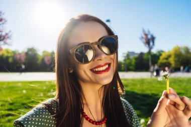 Mutlu gülümseyen komik surat kız darbe karahindiba, yaz güneş gözlüğü, günbatımı