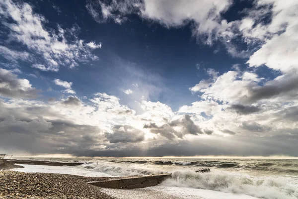 Deserted stone beach at sunset in stormy weather — Stock Photo, Image