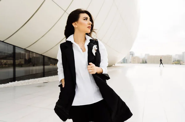 Hermosa chica con estilo en traje de moda negro camina sobre un fondo de edificios modernos en Bakú — Foto de Stock