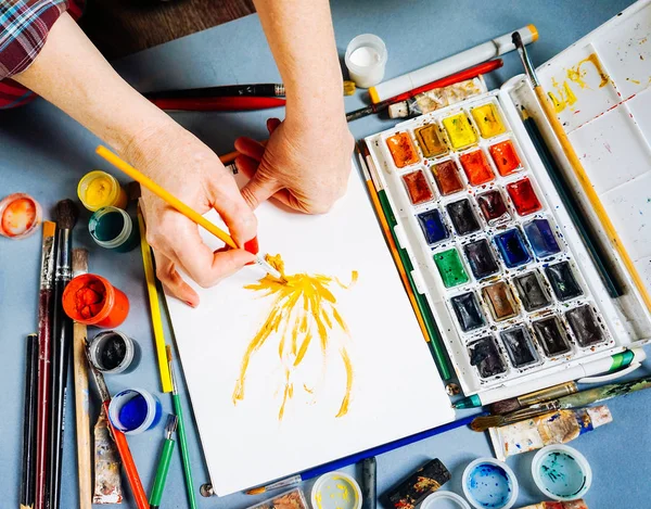 Žena maluje malíř se štětcem a akvarel barvou na bílém papíře — Stock fotografie
