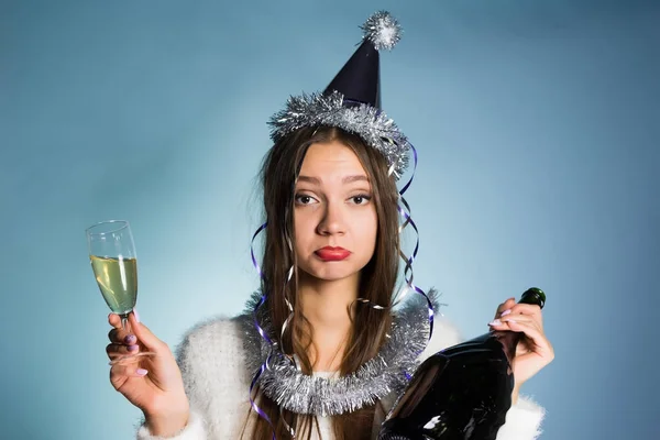 Грустная пьяная девушка празднует Новый год, держит в руках бутылку и бокал шампанского — стоковое фото