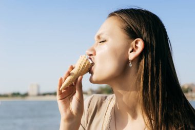 genç bir kız güneşli havalarda parkta yürüyor ve dondurma yiyor
