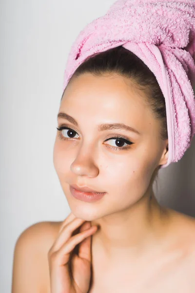 Menina com uma toalha rosa na cabeça em um fundo cinza — Fotografia de Stock