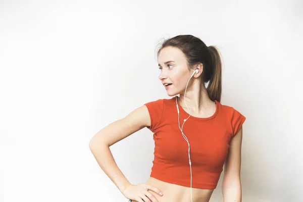 Flickan i orange topp lyssnar på musik i hörlurar. — Stockfoto