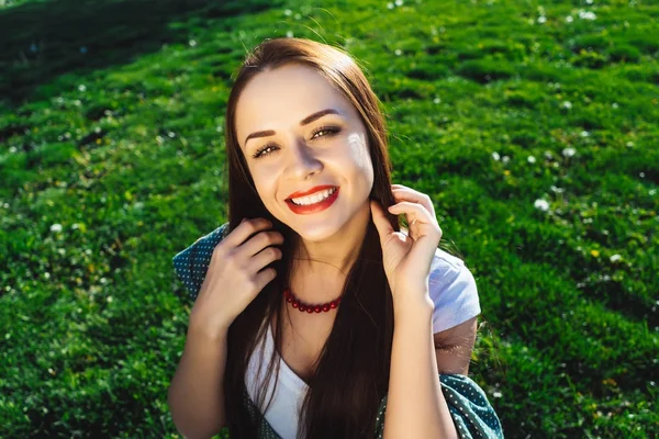 Nahaufnahme Porträt einer Modefrau, die auf Gras sitzt und lächelt — Stockfoto
