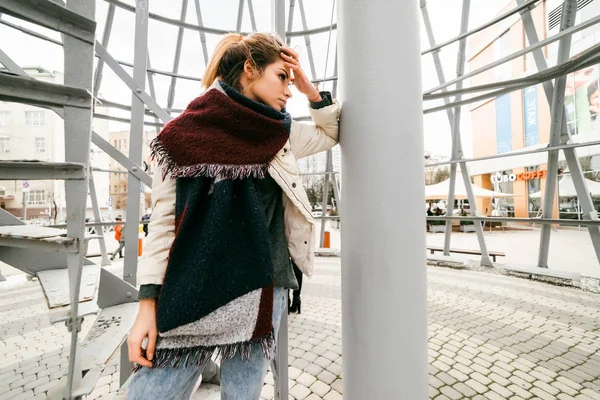 A girl in autumn clothes stands on the background of a spiral staircase — Stock Photo, Image