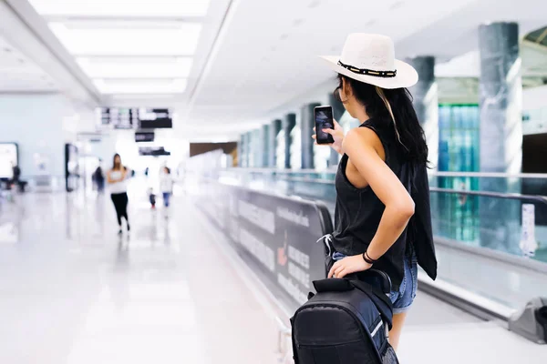 Дівчина в аеропорту з мобільним телефоном в руці, зробити фотографію, використовуючи додаток — стокове фото