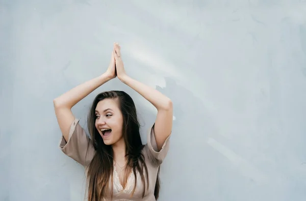 Ung flicka i en sommarklänning står på en grå vägg bakgrund — Stockfoto