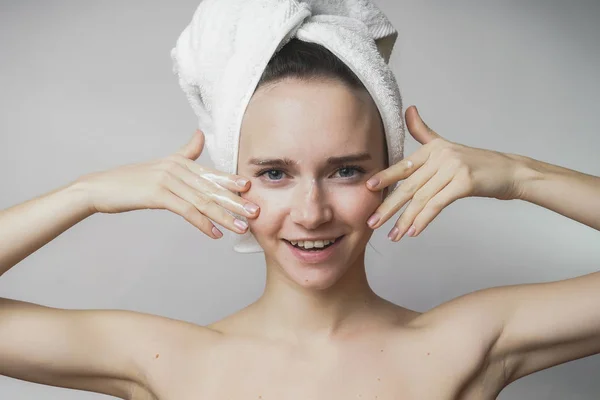 Donna con asciugamano sulla testa facendo massaggio facciale su sfondo bianco — Foto Stock