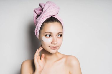 Bir havlu başında genç bir kızla bir maske yüzünde koyar.