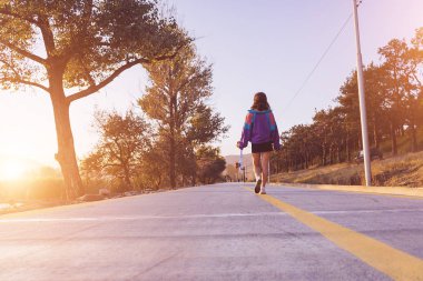 Bir kız sonbahar orman yolu boyunca yürüyor