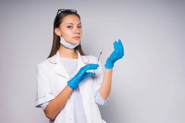 Ung flicka sjuksköterska i glasögon förbereder spruta — Stockfoto
