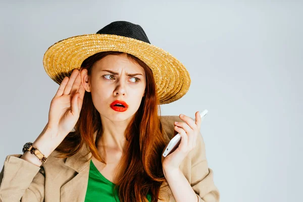 Mulher em um chapéu com as mãos de telefone em um fundo cinza . — Fotografia de Stock