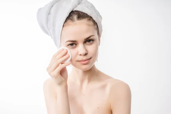 Девушка с полотенцем на голове вытирает лицо хлопковым диском — стоковое фото