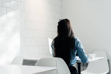 Yalnız siyah saçlı bir kız bir yemekte ofisinde oturur.