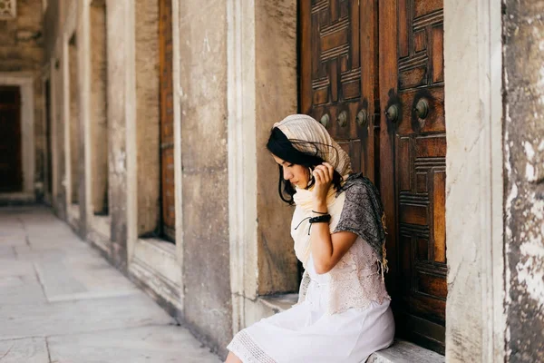 Una joven en una bufanda se sienta en el umbral de una mezquita —  Fotos de Stock