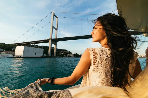 Giovane bella ragazza viaggia in barca, vista sul famoso ponte moderno — Foto Stock