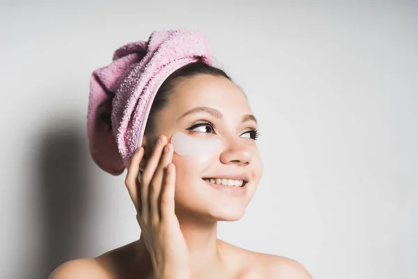 Young girl with a towel on her head puts on face mask — Stock Photo, Image