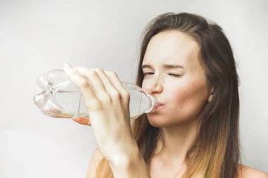 Şişe su üzerinde gri bir arka plan ile kızgın kadın