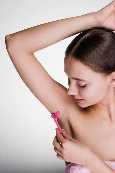 Bela menina rapa o cabelo em suas axilas com uma navalha — Fotografia de Stock