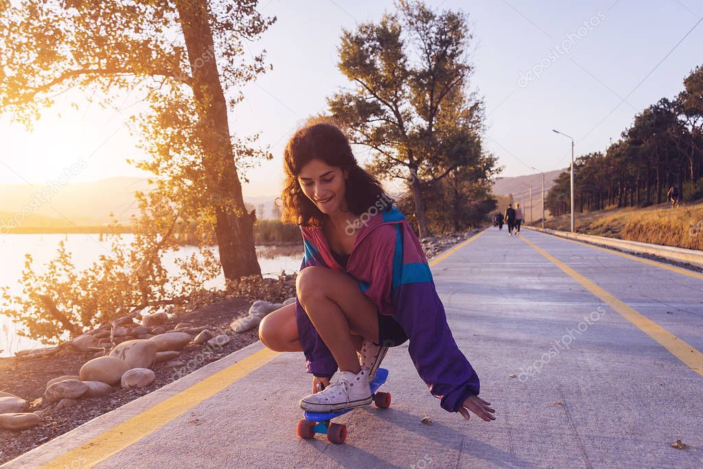 stylish young girl is riding a longboard on the road