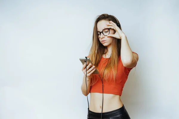 Kadın beyaz bir arka plan üzerinde telefon dinleme ile kulaklık — Stok fotoğraf