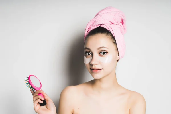 Девушка с розовым полотенцем на голове держит расческу в руках — стоковое фото