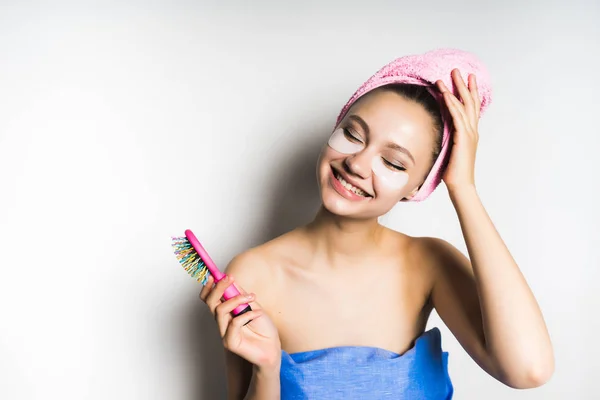Счастливая девушка с полотенцем на голове держит расческу в руках — стоковое фото
