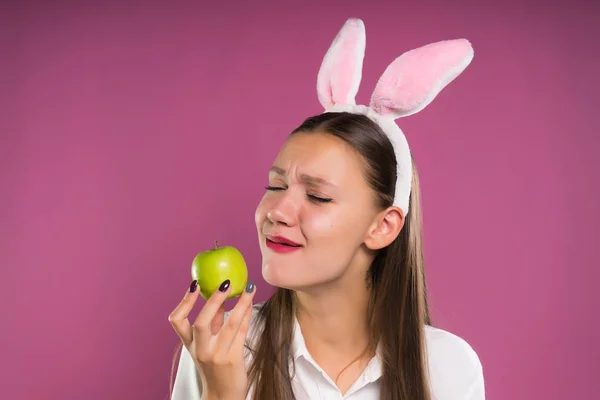 Ung flicka på en rosa bakgrund handlar om att äta sin apple — Stockfoto
