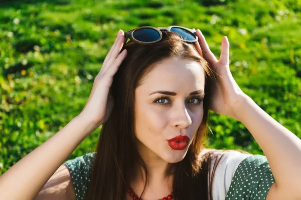 Kadın güneş gözlüğü ile poz surat, bir çim üzerinde kapat