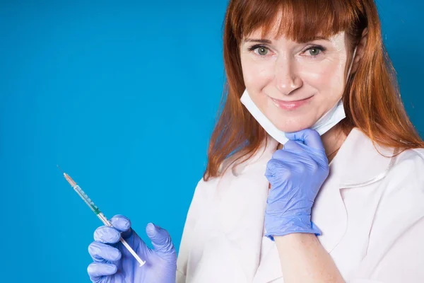 Medico femminile adulto sorridente con una siringa in mano — Foto Stock