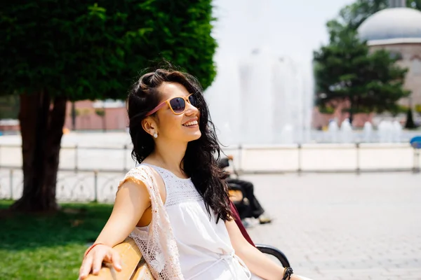Красива дівчина у стані спокою на лавці в Стамбулі, насолоджуючись сонцем на фоні з фонтаном. Студент на літні канікули — стокове фото