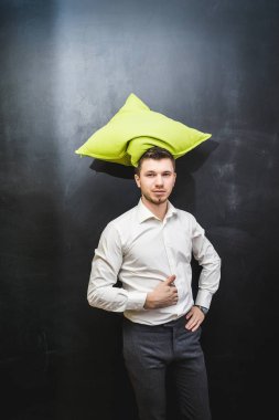 Genç bir adam beyaz gömlekli bir yastık kafasını tutuyor