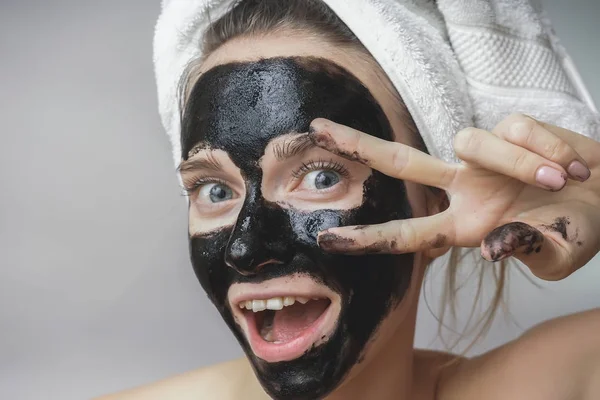 Szczęśliwy radosny kobiety stosowania czarna maska na twarzy. Pielęgnacja skóry, czyste pory, złuszczanie — Zdjęcie stockowe