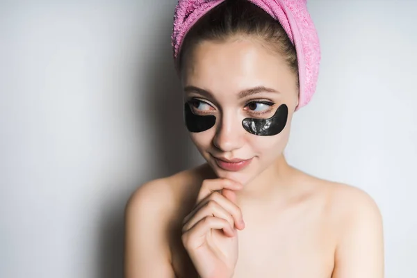 Uma menina com uma toalha rosa na cabeça olha pensativo — Fotografia de Stock