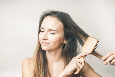 güzel genç kız onun saç beyaz bir arka planda tarama