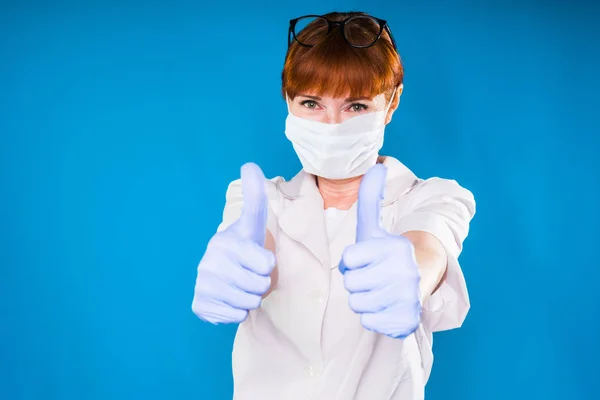 Flicka i vit medicinsk morgonrock och mask på blå bakgrund — Stockfoto