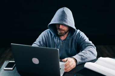 bir dizüstü bilgisayarda yasadışı bir şey yapıyor yüzü, Yetişkin sakallı erkek hacker gizler