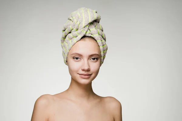 Jovem atraente com pele limpa, na cabeça uma toalha verde, spa dia — Fotografia de Stock