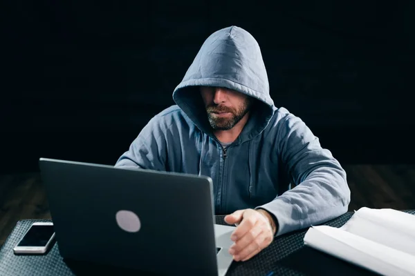 Hacker pria berjanggut dewasa menyembunyikan wajahnya, melakukan sesuatu yang ilegal pada laptop — Stok Foto