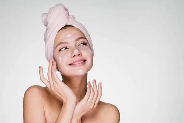 Smiling dreamy girl wants to be beautiful, put cream on her face — Stock Photo, Image